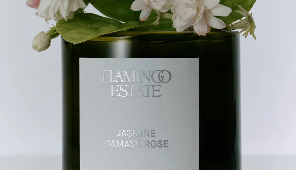Flamingo Estate brand candle with jasmine damask rose fragrance and floral arrangement on a white background