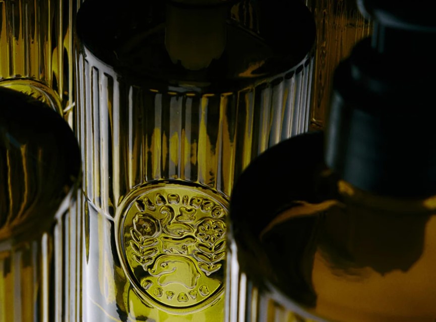 Close-up of a yellow-green glass bottle with a decorative emblem on a dark background.