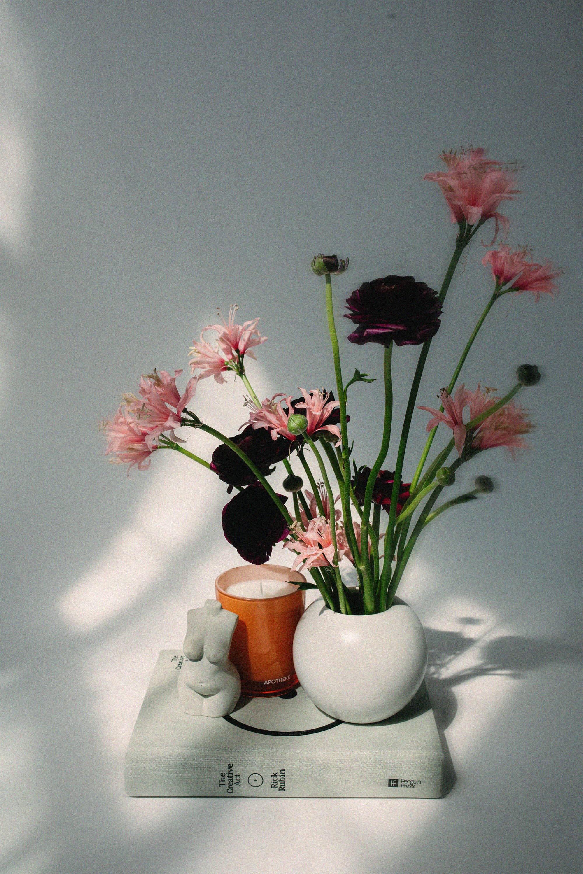 Vase with flowers on a white surface with a gray background.