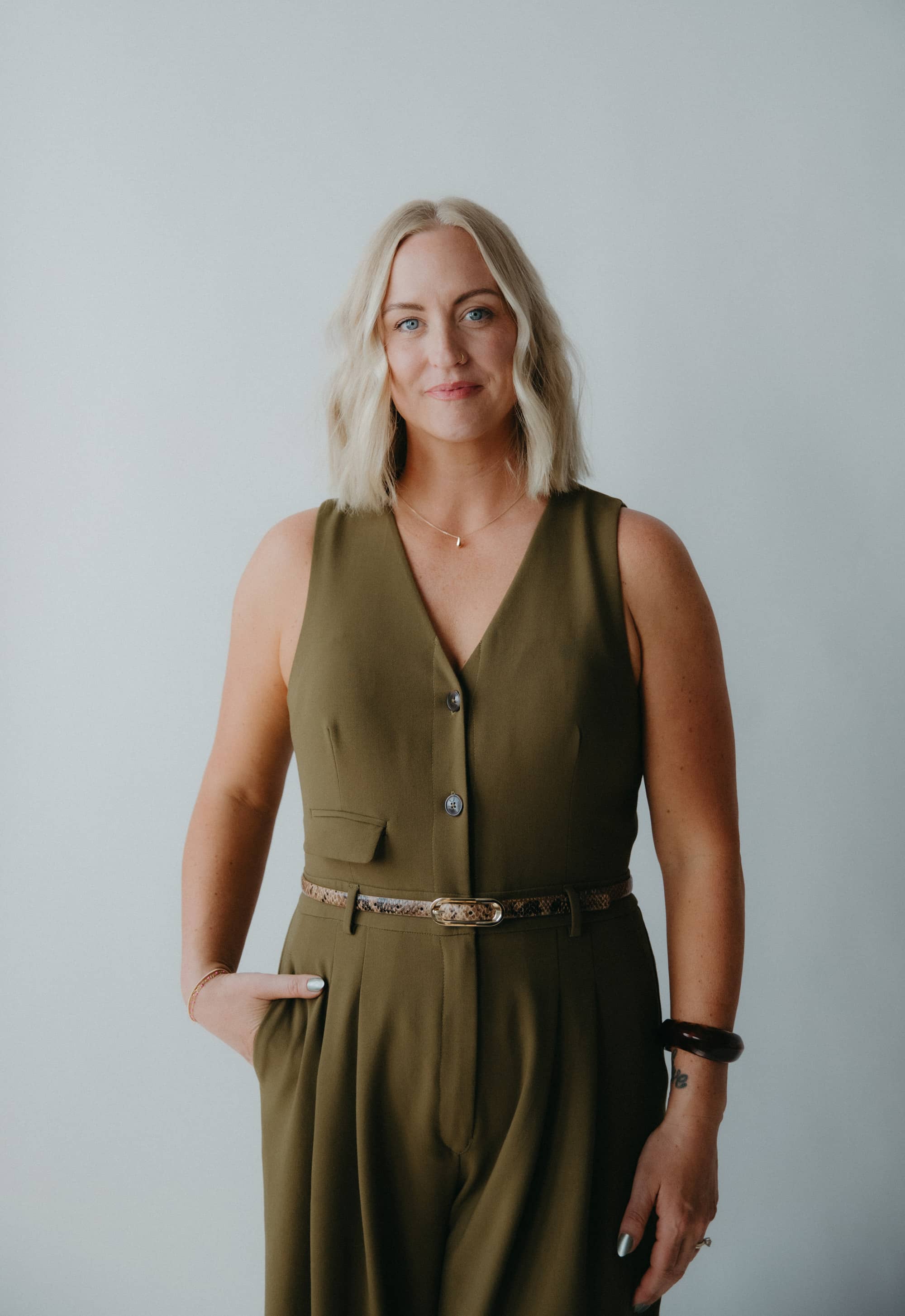 Woman wearing a green jumpsuit against a plain background.
